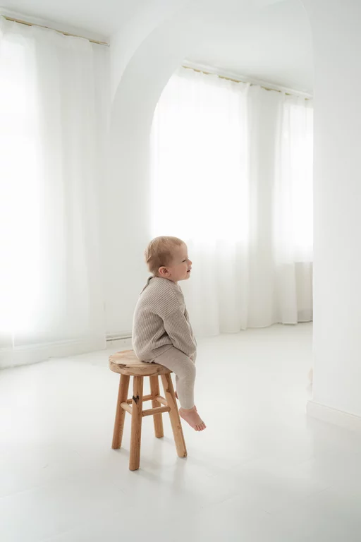 Zeitlose Familienbilder im hellen Fotostudio in Brandenburg, Kind sitzt auf Holzhocker